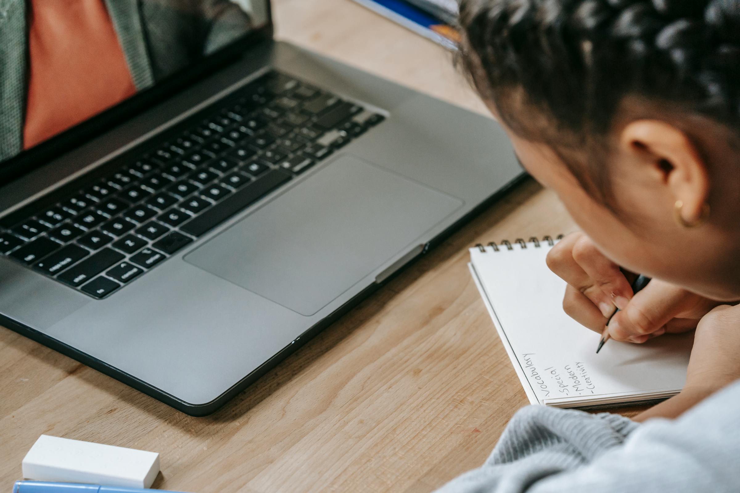 Student studying beside a laptop